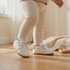 Un bebé camina con los zapatos blancos con cordones