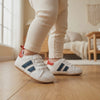 Un bebé camina con los zapatos deportiva marino y roja