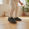 Un bebé camina con los zapatos verde militar