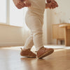 Un bebé da un paso con los zapatos de piel de la mano de su madre