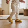 Un bebé camina con los zapatos mostaza