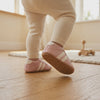 Un bebé camina con los zapatos rosa con rayas