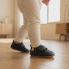 Un bebé camina con los zapatos negros con velcro