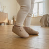 Un bebé camina con los zapatos beige con cordones